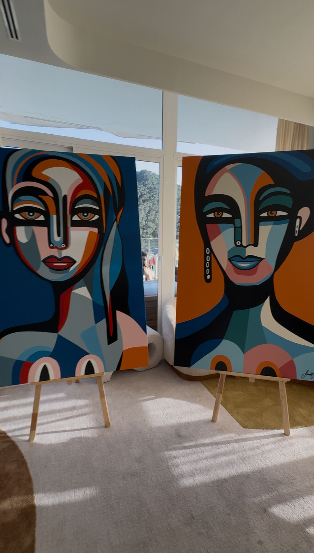 Cubist portrait diptych on easels by the window.