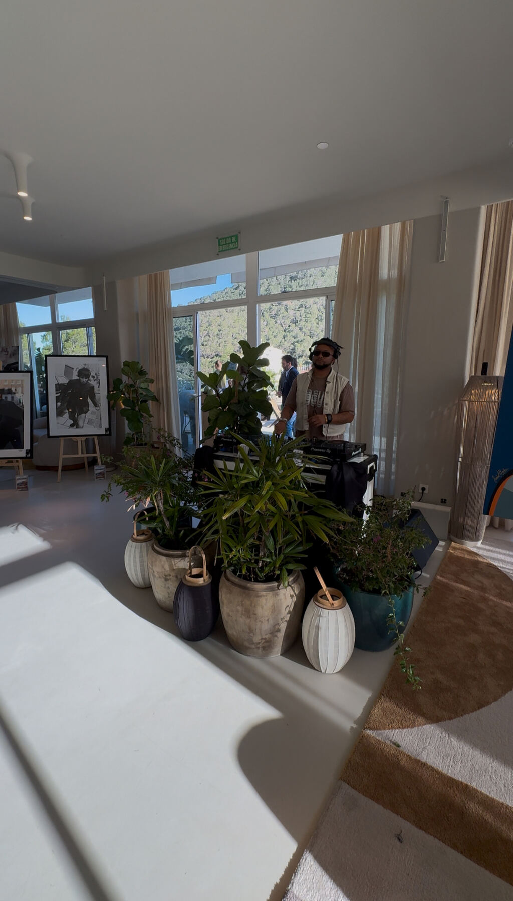 Daytime set — DJ booth framed by plants and photographic prints.